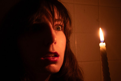 woman looking frightened with candle flame